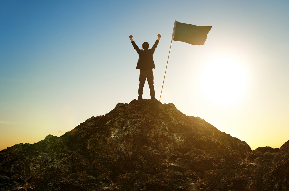 business, success, leadership, achievement and people concept - silhouette of businessman with flag on mountain top over sky and sun light background